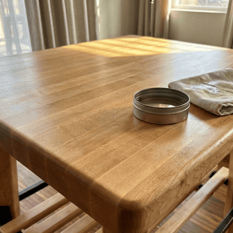 Wooden table with a metal container and cloth on a wooden floor.
