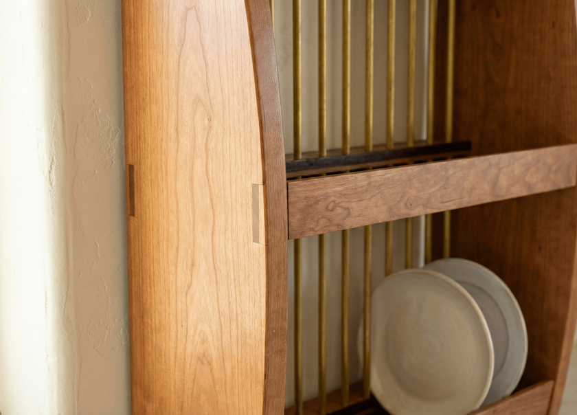 Wooden cabinet with a glass door displaying ceramic plates.