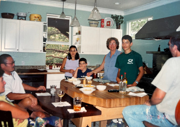 Family gathering in a kitchen with people sitting around a table.