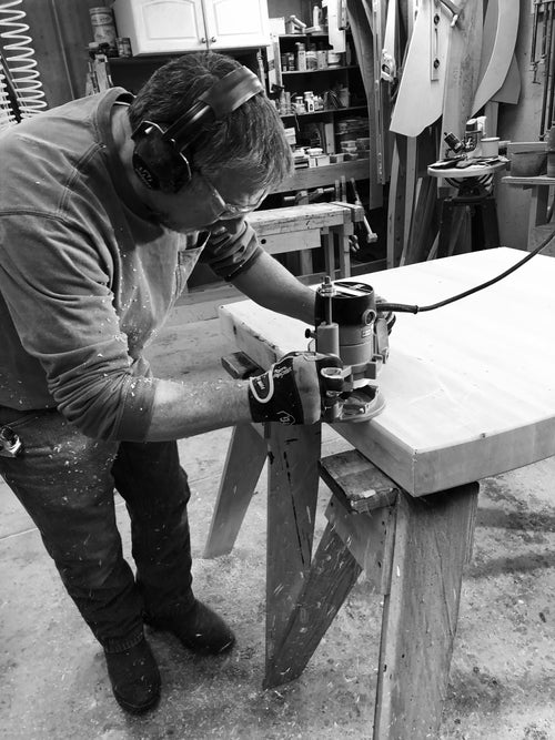Person using a router on a piece of wood in a workshop setting