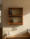 Wooden wall-mounted shelf with wine glasses and books in a home setting