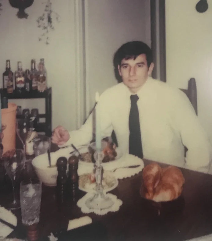 Man sitting at a table with drinks and food, vintage setting