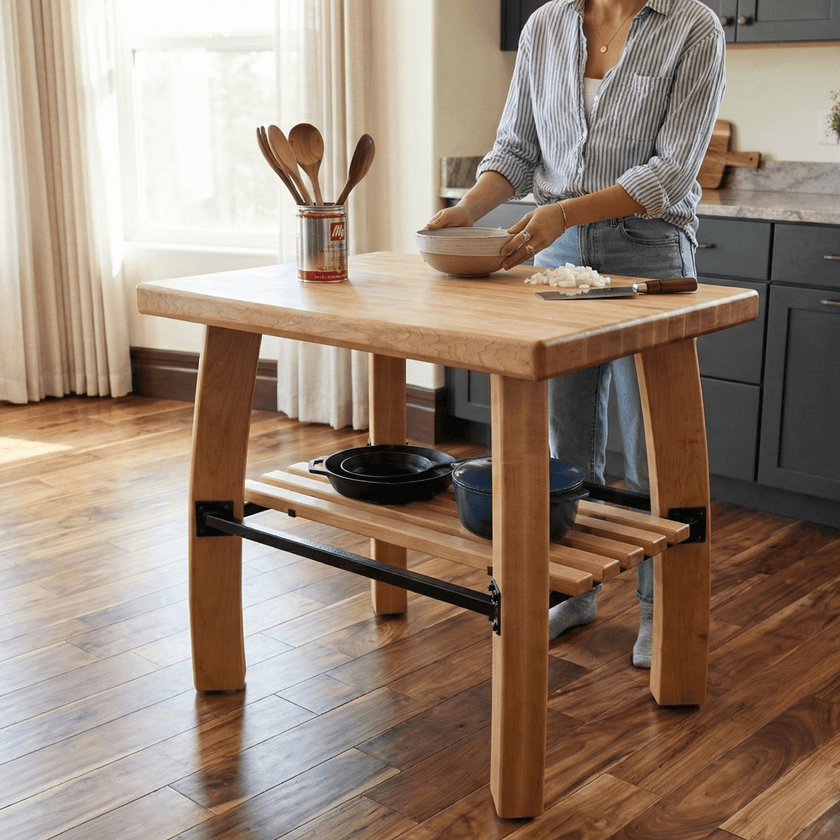 Person preparing food at a wooden kitchen island with utensils and a bowl.