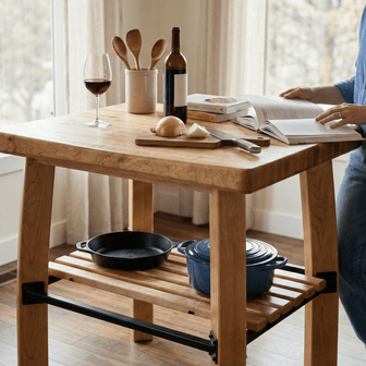 Person standing by a wooden kitchen island with cookware and a book